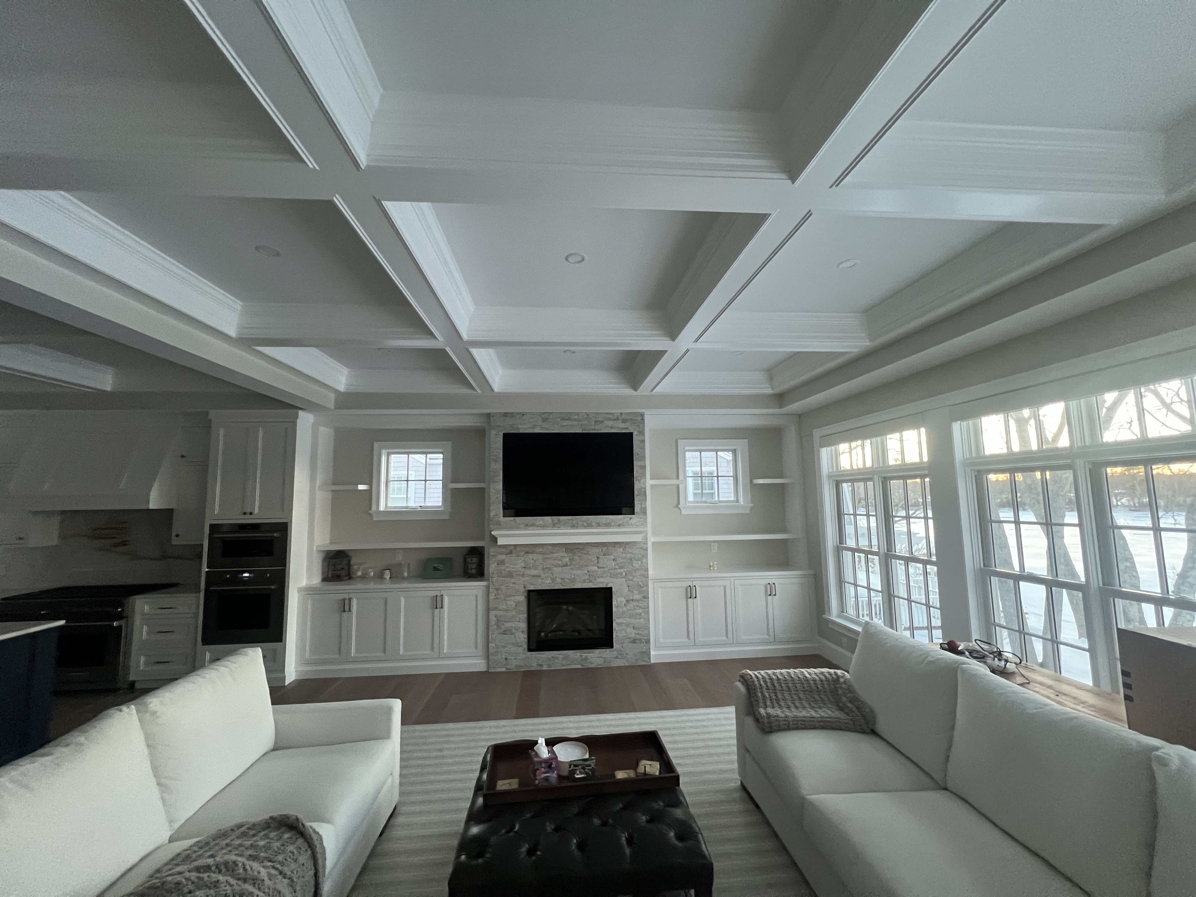 A finished living space with a coffered ceiling, detailed trim and built-in cabinetry.